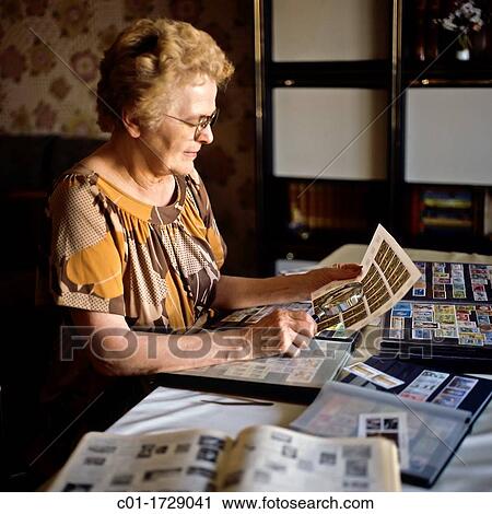 Stock Image - elderly woman with postage stamp collection. Fotosearch