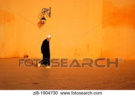 Stock Image - Eldery moroccan man in traditional clothes on his way to The Mosque, Koutubia Mosque, Marrakech, Morocco. Fotosearch