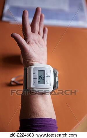 Stock Photo - Eldery woman checking her blood pressure at home.. Fotosearch