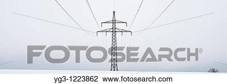 Stock Image - Electircal power lines on cloudy winter day cross snow covered field, Oberpfalz, Bavaria, Germany. Fotosearch