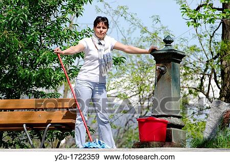 Elegant and proud woman with cleaning mop and filling up her bucket with water from a fountain View Large Photo Image Stock Photo - Elegant and proud woman with cleaning mop and filling up her bucket with water from a fountain. Fotosearch