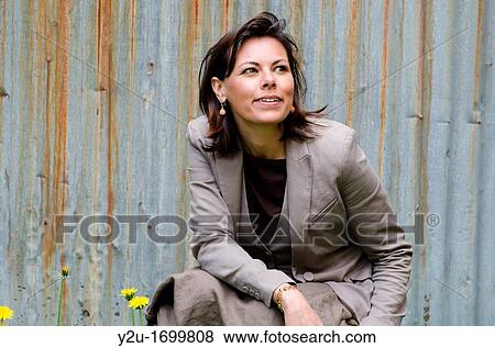 Stock Photo - Elegant and satisfied woman sitting down and watching up. Fotosearch