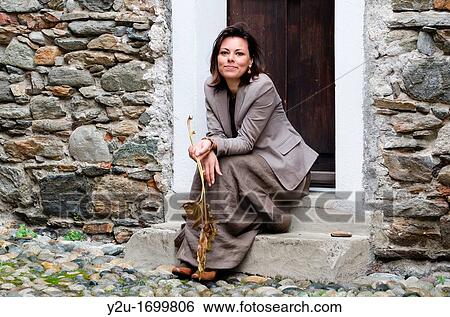 Elegant and satisfied woman sitting down with tree blade on rustic stairs View Large Photo Image Stock Photograph - Elegant and satisfied woman sitting down with tree blade on rustic stairs. Fotosearch