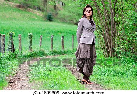 Elegant woman standing up on a forest road close to a fence View Large Photo Image Stock Photography - Elegant woman standing up on a forest road close to a fence. Fotosearch