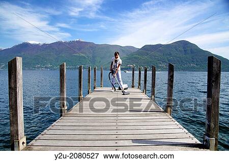 Elegant woman with a vacuum cleaner on a pier over an alpine lake maggiore with snow-capped mountain in ticino switzerland. View Large Photo Image Stock Photo - Elegant woman with a vacuum cleaner on a pier over an alpine lake maggiore with snow-capped mountain in ticino switzerland.. Fotosearch