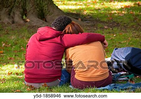 embracing couple sitting together on a grass full of dried leaves in a park, symbol of autumn, Geneva, Switzerland View Large Photo Image Stock Photograph - embracing couple sitting together on a grass full of dried leaves in a park, symbol of autumn, Geneva, Switzerland. Fotosearch