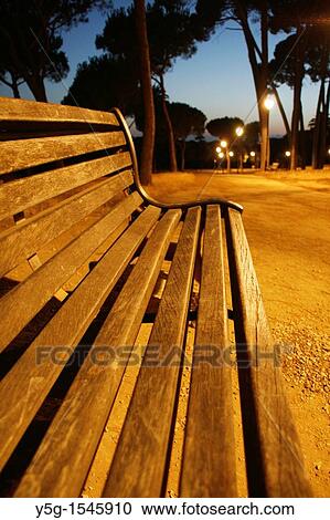 Stock Image - empty bench in villa pamphili park in rome at night. Fotosearch