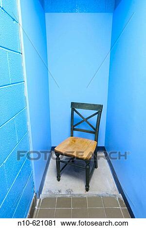 Stock Image - Empty chair in a narrow hallway.. Fotosearch
