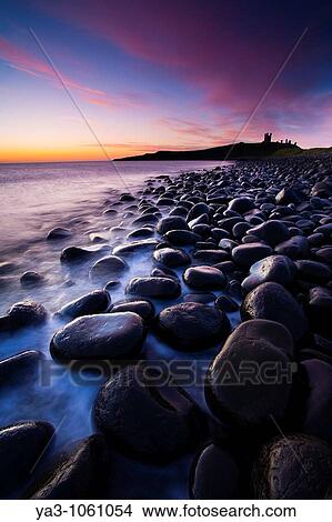 England, Northumberland, Embleton Bay Waves crash againt the sea scultured rocks dominating the coastline of Embleton Bay, overlooked by the dramatic ruins of Dunstanburgh Castle View Large Photo Image Picture - England, Northumberland, Embleton Bay Waves crash againt the sea scultured rocks dominating the coastline of Embleton Bay, overlooked by the dramatic ruins of Dunstanburgh Castle. Fotosearch
