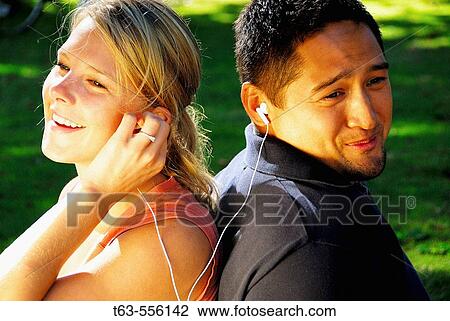 ethnic male and caucasion female listening to music together View Large Photo Image Stock Image - ethnic male and caucasion female listening to music together. Fotosearch