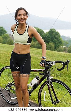 Ethnic woman in exercise clothing with bicycle in scenic setting View Large Photo Image Stock Photograph - Ethnic woman in exercise clothing with bicycle in scenic setting. Fotosearch