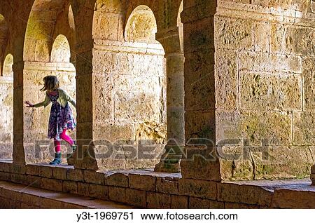 Stock Image - Europe, France, Var, Le Thoronet, Cistercian Abbey. Young girl playing in the The cloister.. Fotosearch