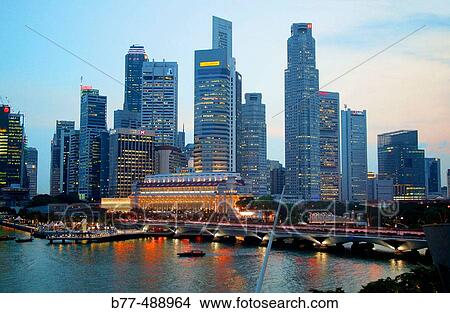 Picture - Evening view of the Singapore skyline from Marina Bay, with Esplanade Bridge, Fullerton Hotel and Merlion. Singapore.. Fotosearch