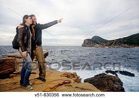 Stock Photograph - Excursionist couple in a cliff by the sea. Fotosearch