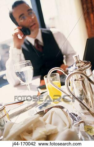 Executive man sitting in a breakfast table in a hotel room while talking on cellular phone View Large Photo Image Stock Image - Executive man sitting in a breakfast table in a hotel room while talking on cellular phone. Fotosearch