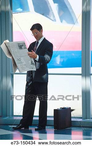 Executive reading newspaper in the airport View Large Photo Image Picture - Executive reading newspaper in the airport. Fotosearch