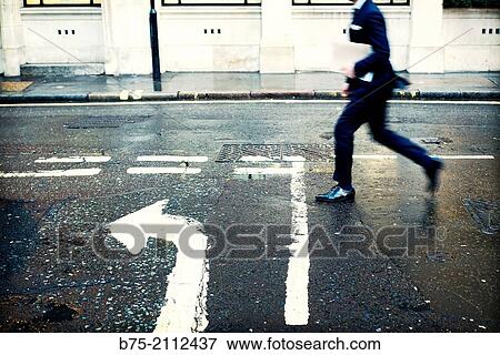 executive unrecognizable man, with a folder under his arm walking down the street with an arrow painted on the asphalt. City of London, England, UK, Europe. View Large Photo Image Stock Photo - executive unrecognizable man, with a folder under his arm walking down the street with an arrow painted on the asphalt. City of London, England, UK, Europe.. Fotosearch