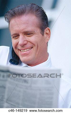 Executive with financial newspaper talking on cell phone View Large Photo Image Stock Photo - Executive with financial newspaper talking on cell phone. Fotosearch