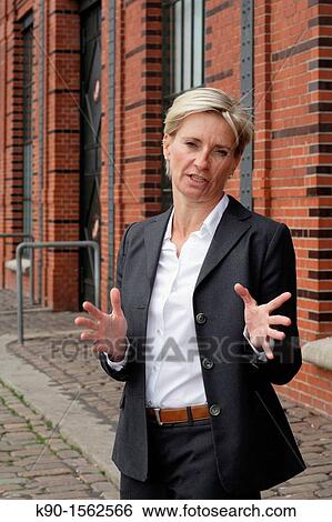 Executive woman, serious talking with open gesture, office building made of red bricks, Hamburg, Germany, Europe View Large Photo Image Stock Photograph - Executive woman, serious talking with open gesture, office building made of red bricks, Hamburg, Germany, Europe. Fotosearch