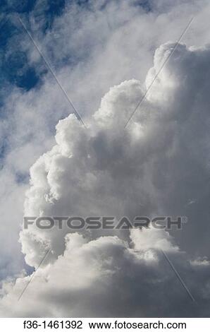 Stock Image - Expanding cumulus strong storm clouds expanding in air below higher cirrus clouds, California. Fotosearch