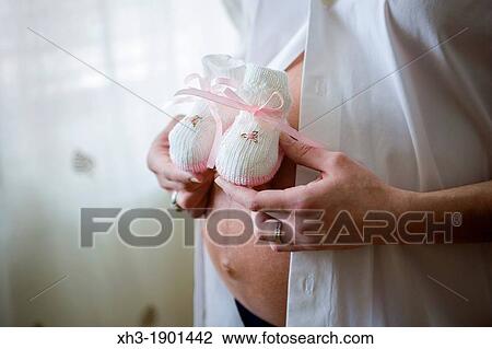 Expectant mother holding pink booties on belly View Large Photo Image Stock Image - Expectant mother holding pink booties on belly. Fotosearch