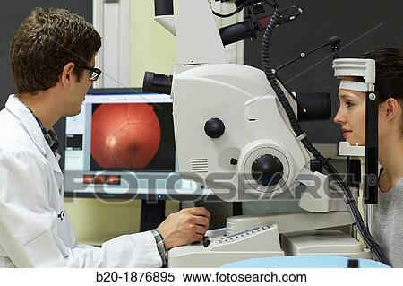 Stock Photography - Eye examination Doctor using a retinal camera during an angiography examination of a patient's eye. Fotosearch