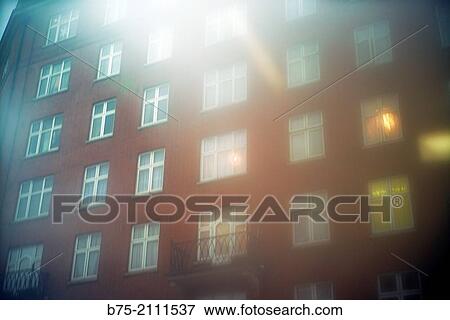 Stock Photo - Facade of an apartment building with illuminated windows at sunset in London, England, UK, Europe. Fotosearch