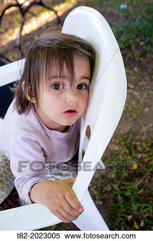 Stock Photography - Face of 2 year old girl reclining on a chair looking at camera spit. Sevilla, Andalucia, Spain, Europe.. Fotosearch