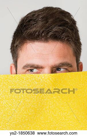 Face of adult male peeking and looking sideways hidden behind sandpaper View Large Photo Image Stock Photo - Face of adult male peeking and looking sideways hidden behind sandpaper. Fotosearch