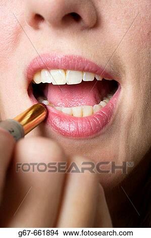 Facial close up of mid 20's woman applying lipstick to her lips View Large Photo Image Picture - Facial close up of mid 20's woman applying lipstick to her lips. Fotosearch