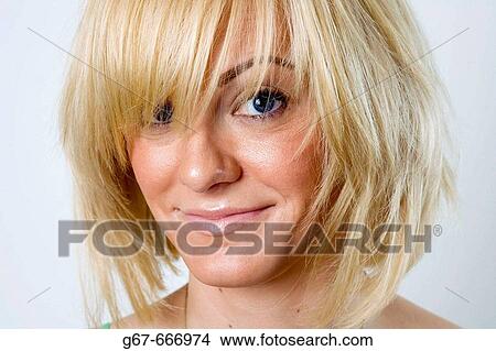 Facial close up of miud 20's caucasian woman with blond hair obscuring her eyes during studio portrait photo shoot. View Large Photo Image Picture - Facial close up of miud 20's caucasian woman with blond hair obscuring her eyes during studio portrait photo shoot.. Fotosearch