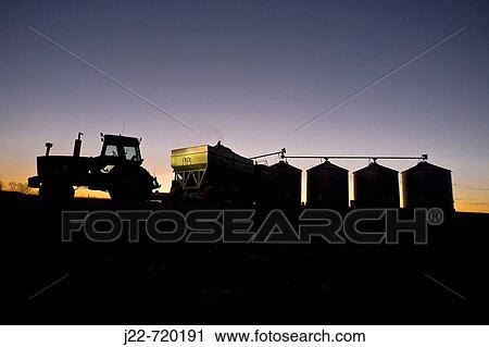 Fall corn harvest in Hardin County Iowa with silhouetted tractor and wagon unloading at state of the art computer aided grain drying bins near Buckeye, Iowa, USA, at twilight View Large Photo Image Stock Image - Fall corn harvest in Hardin County Iowa with silhouetted tractor and wagon unloading at state of the art computer aided grain drying bins near Buckeye, Iowa, USA, at twilight. Fotosearch