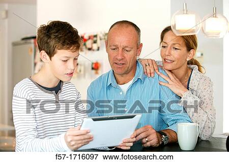 Family at home using tablet computer View Large Photo Image Stock Photo - Family at home using tablet computer. Fotosearch