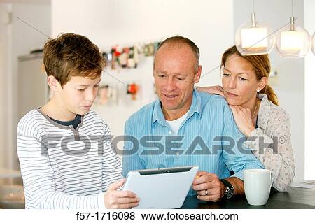Family at home using tablet computer View Large Photo Image Stock Photo - Family at home using tablet computer. Fotosearch