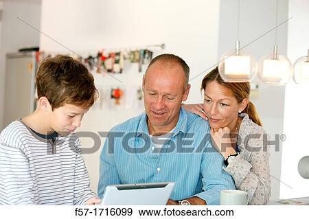 Family at home using tablet computer View Large Photo Image Stock Photo - Family at home using tablet computer. Fotosearch