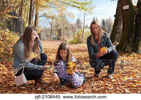 Stock Photography - Family collecting fallen autumn leaves.. Fotosearch