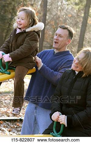 Stock Photo - family having fun on a see-saw in a park. Fotosearch