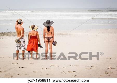 Stock Image - Family looking at surf, Playa Carmen, Costa Rica.. Fotosearch