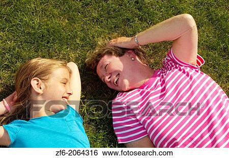 Family love of Grandmother and grandaughter daughter laying in grass at home hugging and caring in sunshine smiling happy and joy. View Large Photo Image Stock Photograph - Family love of Grandmother and grandaughter daughter laying in grass at home hugging and caring in sunshine smiling happy and joy.. Fotosearch