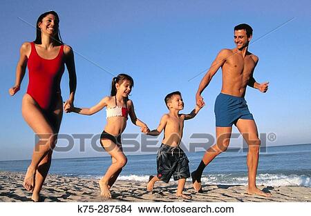 Picture - family of four running along the seashore. Fotosearch