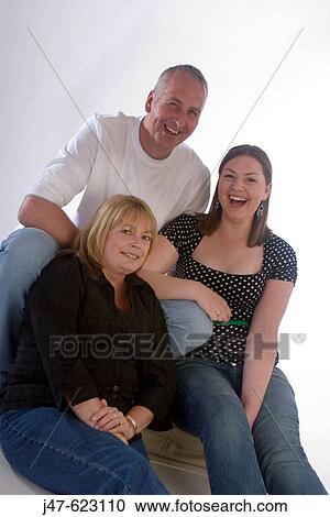 Stock Image - Family of three, mother daughter and father, smiling into camera, full length. Fotosearch