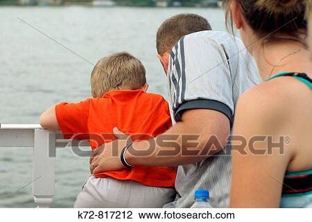 Stock Image - Family on a boat ride looking down into the water.. Fotosearch