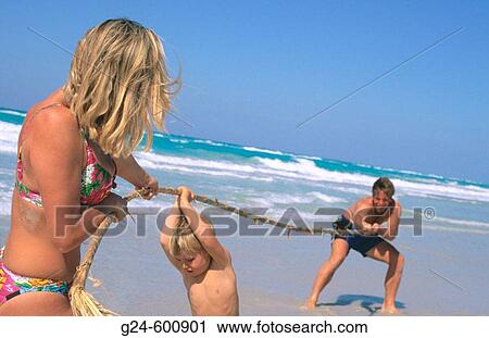 Stock Image - Family on the beach, having? tug-of-war? with bamboo. Fotosearch