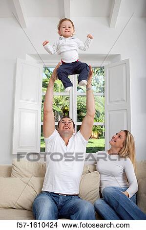 Family on their sofa throwing one year old baby in the air View Large Photo Image Picture - Family on their sofa throwing one year old baby in the air. Fotosearch