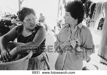 Stock Image - Family planning motivator and woman at a public washing place. Guatemala City. Guatemala. Fotosearch