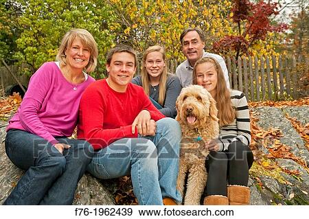 Family portrait, including goldendoodle poodle golden retriever mix in back yard of suburban home View Large Photo Image Stock Photo - Family portrait, including goldendoodle poodle golden retriever mix in back yard of suburban home. Fotosearch
