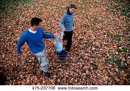 Family running through fallen leaves View Large Photo Image Stock Photograph - Family running through fallen leaves. Fotosearch