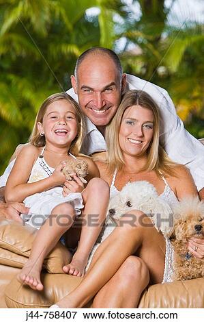 Family sitting on a chair with poodle dogs, smiling, portrait View Large Photo Image Stock Photo - Family sitting on a chair with poodle dogs, smiling, portrait. Fotosearch