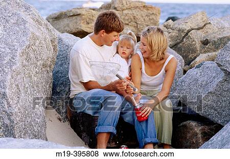 family sitting on the rocks at the beach View Large Photo Image Stock Photo - family sitting on the rocks at the beach. Fotosearch