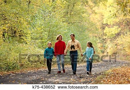 Stock Image - Family walking down country road in the fall. Fotosearch